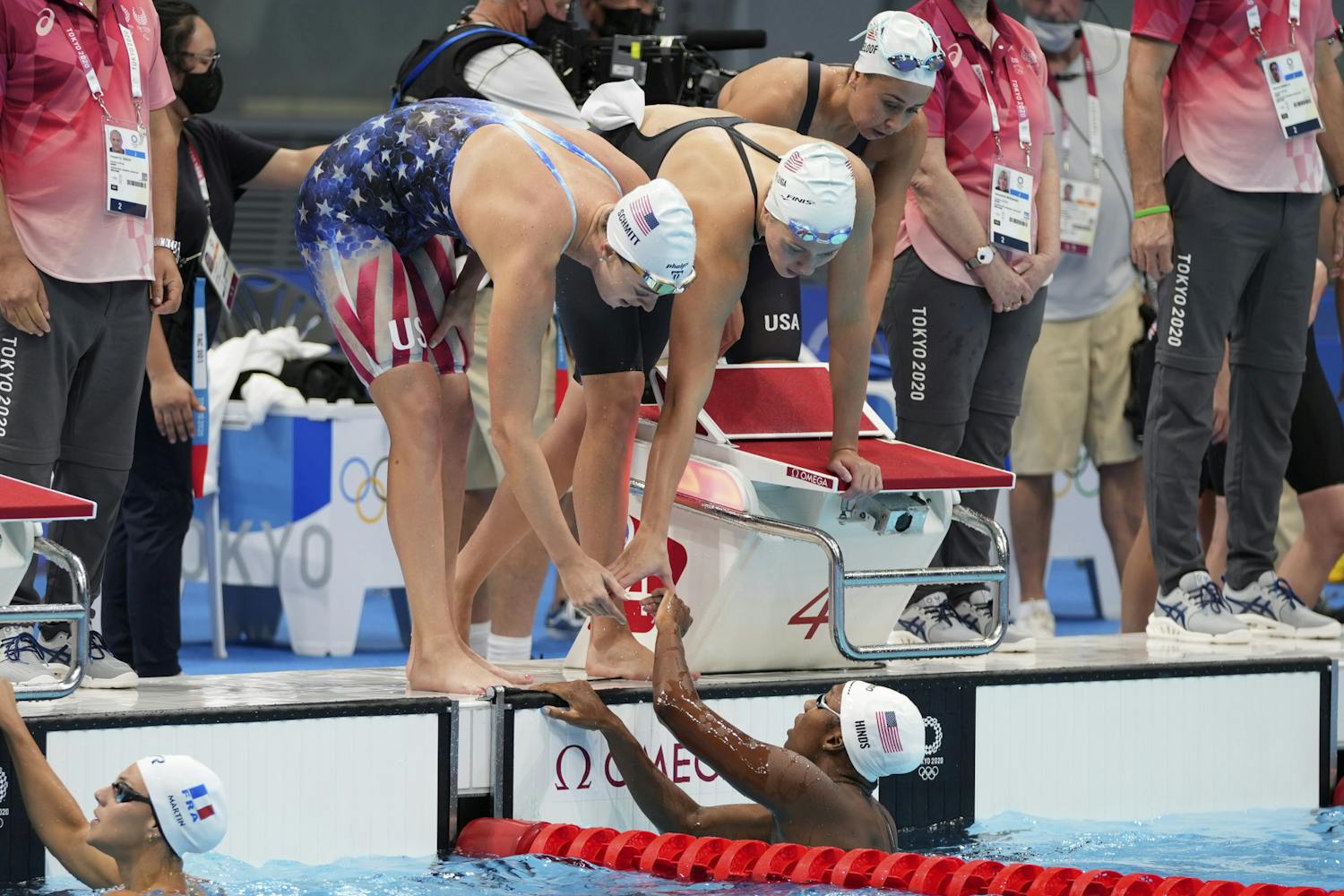 Natalie Hinds, bottom, of the United States is congratulated by teammates after swimming the fourth leg during a preliminary round of the women's 4x100m freestyle relay at the 2020 Summer Olympics, Saturday, July 24, 2021, in Tokyo, Japan. (AP Photo/Matthias Schrader)