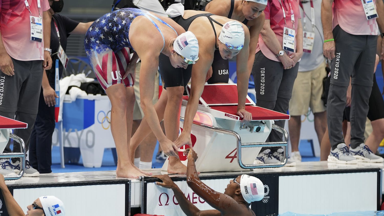 Natalie Hinds, bottom, of the United States is congratulated by teammates after swimming the fourth leg during a preliminary round of the women's 4x100m freestyle relay at the 2020 Summer Olympics, Saturday, July 24, 2021, in Tokyo, Japan. (AP Photo/Matthias Schrader)