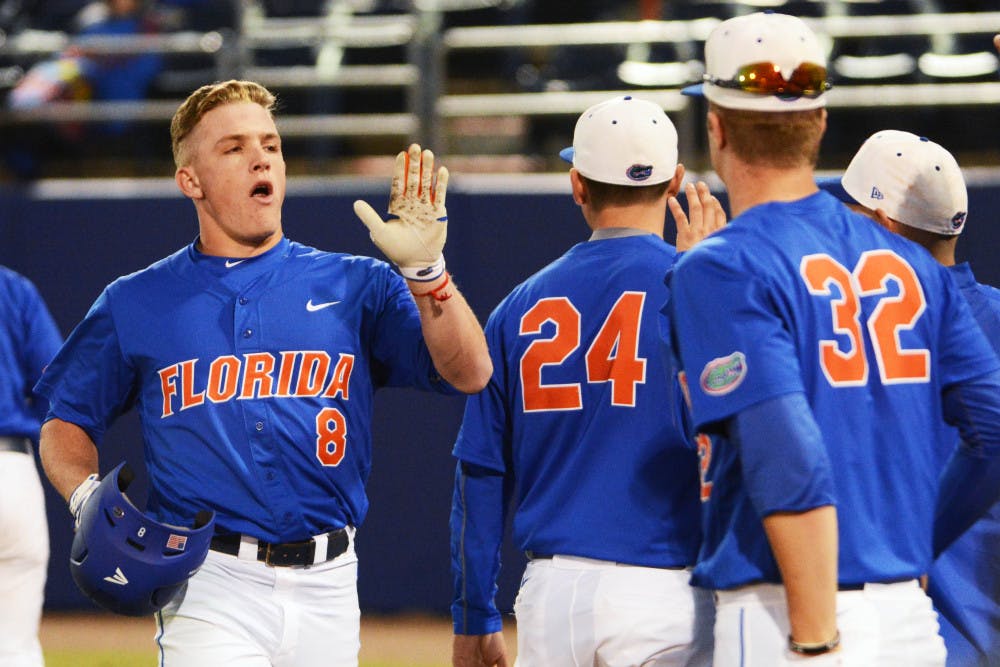 Harrison Bader (8) celebrates with teammates following his second home run during Florida's 22-3 win against Rhode Island on Feb. 14 at McKethan Stadium.