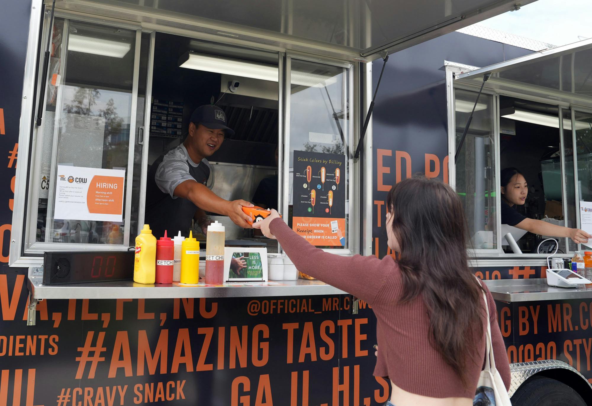 James Lee, co-founder of Mr. Cow Corndog, serves customers at Midpoint Park Eatery on Saturday, Sept. 2, 2023. 