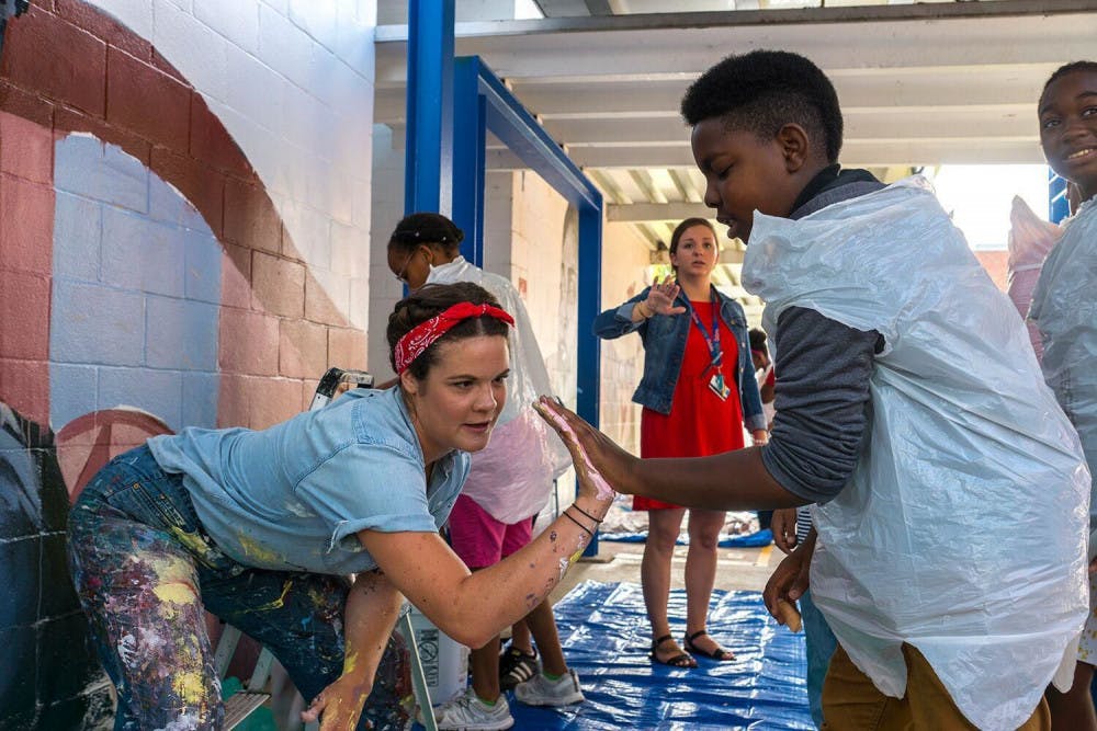 Artist Jenna Horner helps students apply paint to their hands. Photo by Iryna Kanishcheva.
&nbsp;