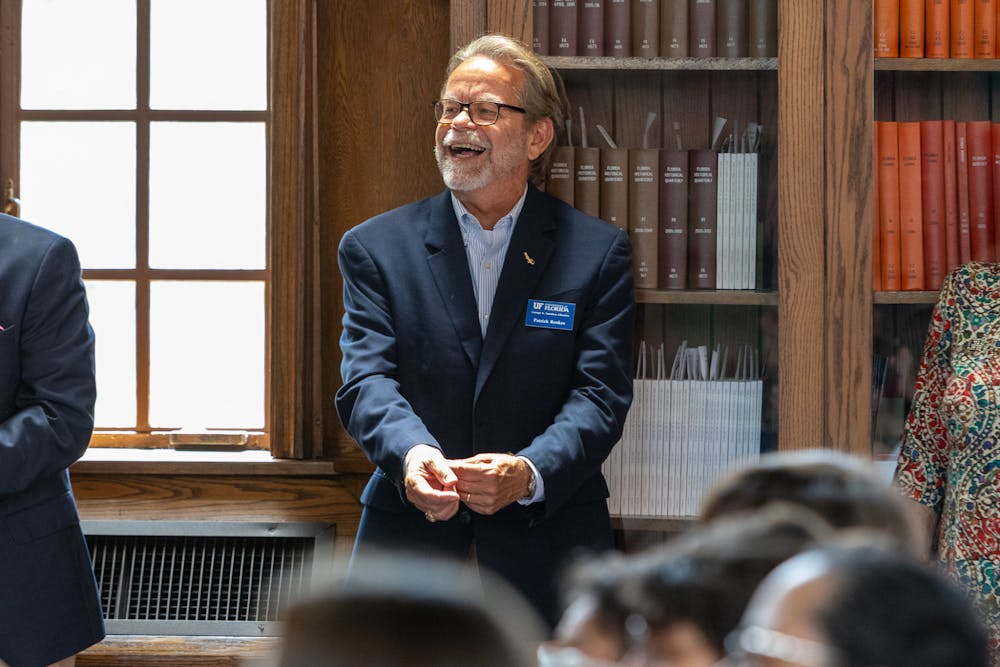 <p>Patrick Reakes, interim-director of UF libraries, laughs during former Dean Judy Russell’s farewell celebration at Smathers Library.   </p><p></p>