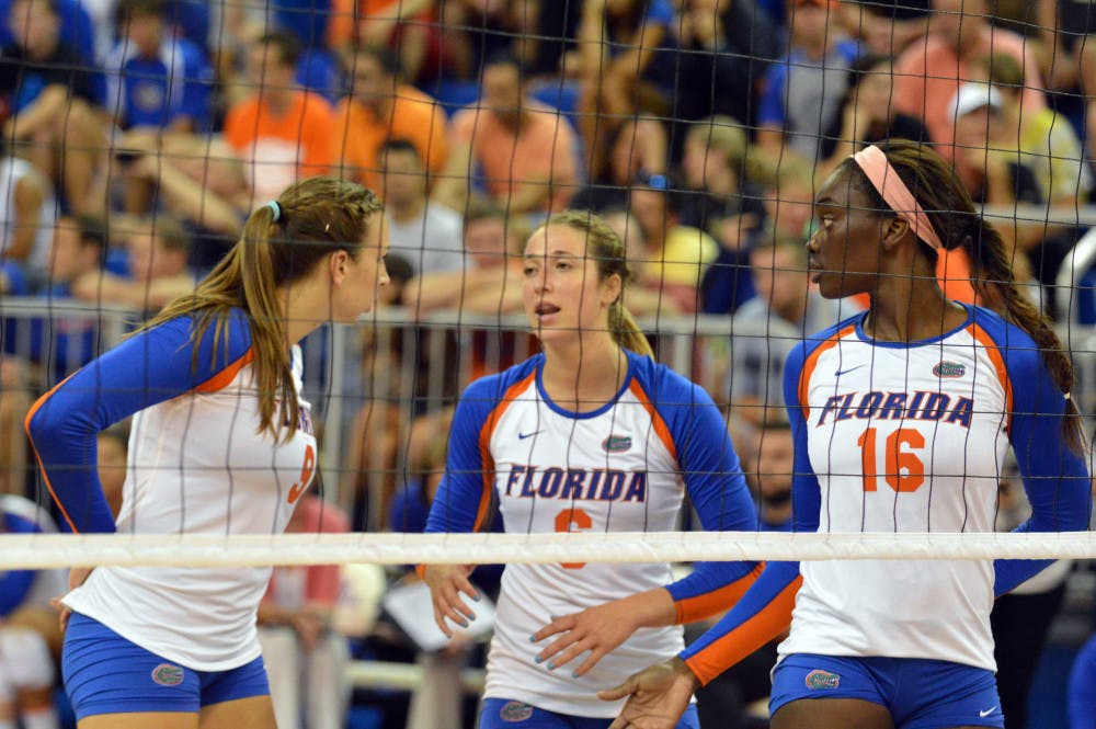 Setter Mackenzie Dagostino (center) talks to outside hitter Ziva Recek (left) and middle blocker Simone Antwi (right) before a play during Florida's 3-0 win against Idaho.