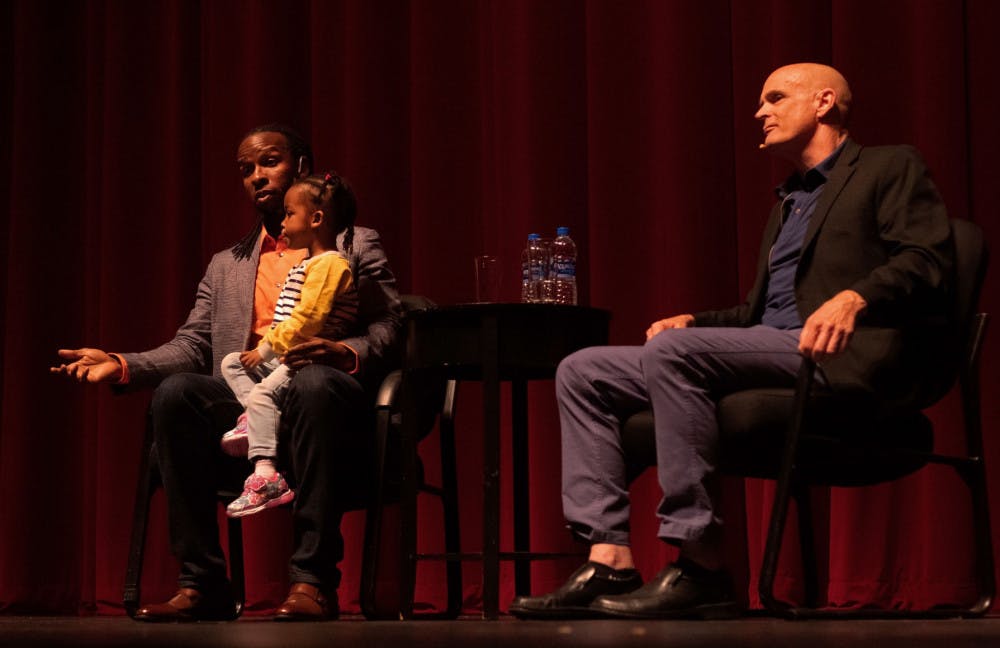 Ibram X. Kendi answers an audience question during a question and answer session moderated by author and history professor Jack Davis while Kendi’s daughter sits in his lap at the Phillips Center for the Performing Arts Thursday night. About 1,230 people attended the event.