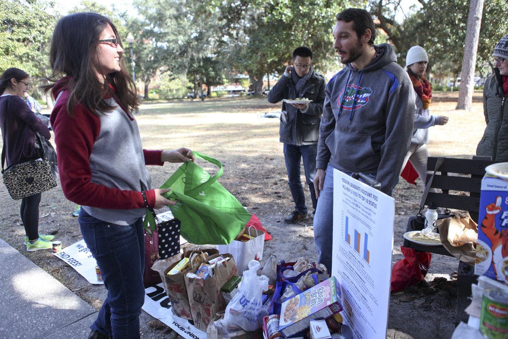 <p class="p1">UF English sophomore Petrana Radulovic, 18, donated food to Thanksgiving, which goes to graduate assistants, on Thursday while talking to UF history graduate student Kyle Bridge, 24.&nbsp;</p>
