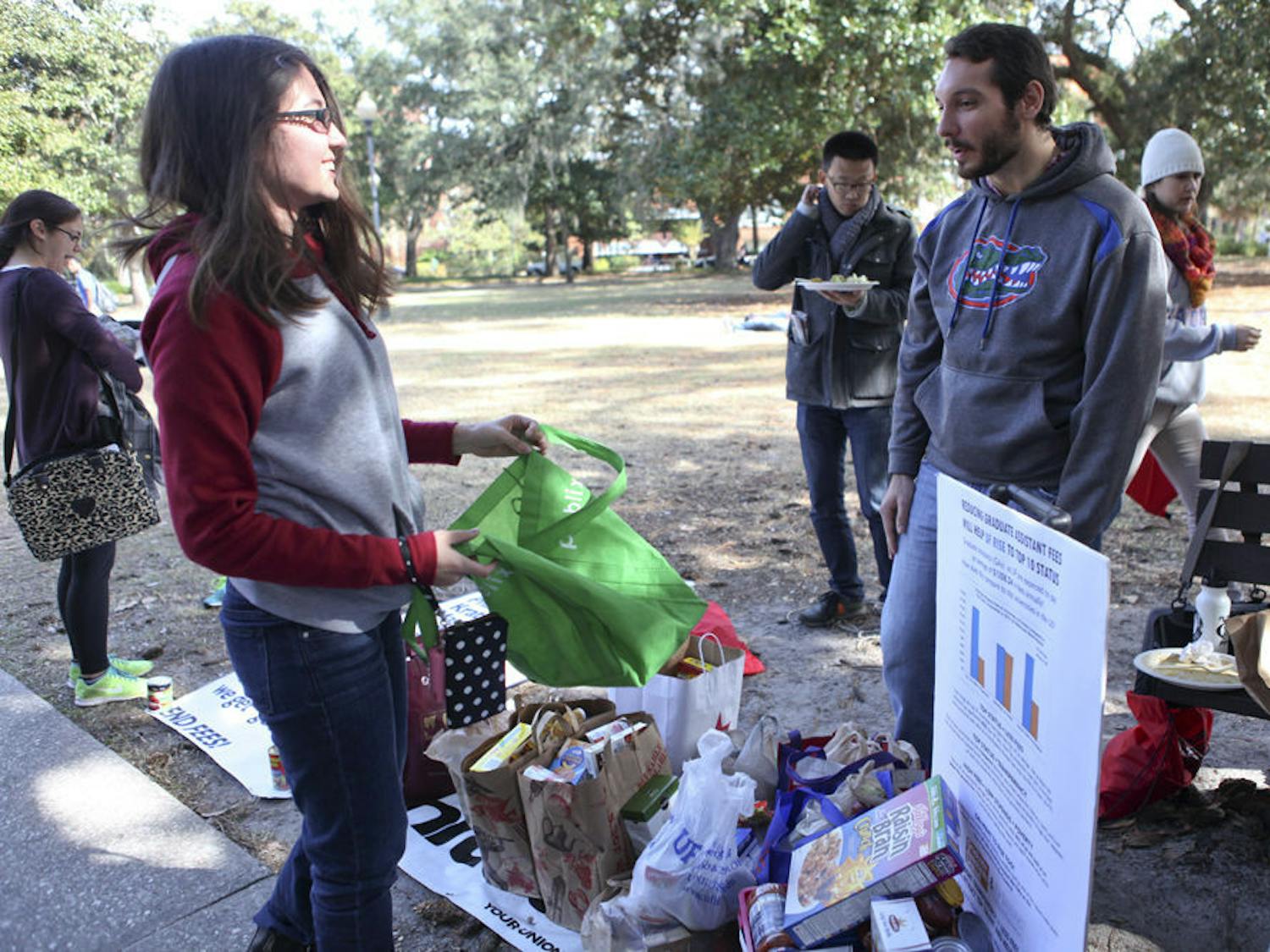 UF English sophomore Petrana Radulovic, 18, donated food to Thanksgiving, which goes to graduate assistants, on Thursday while talking to UF history graduate student Kyle Bridge, 24.&nbsp;
