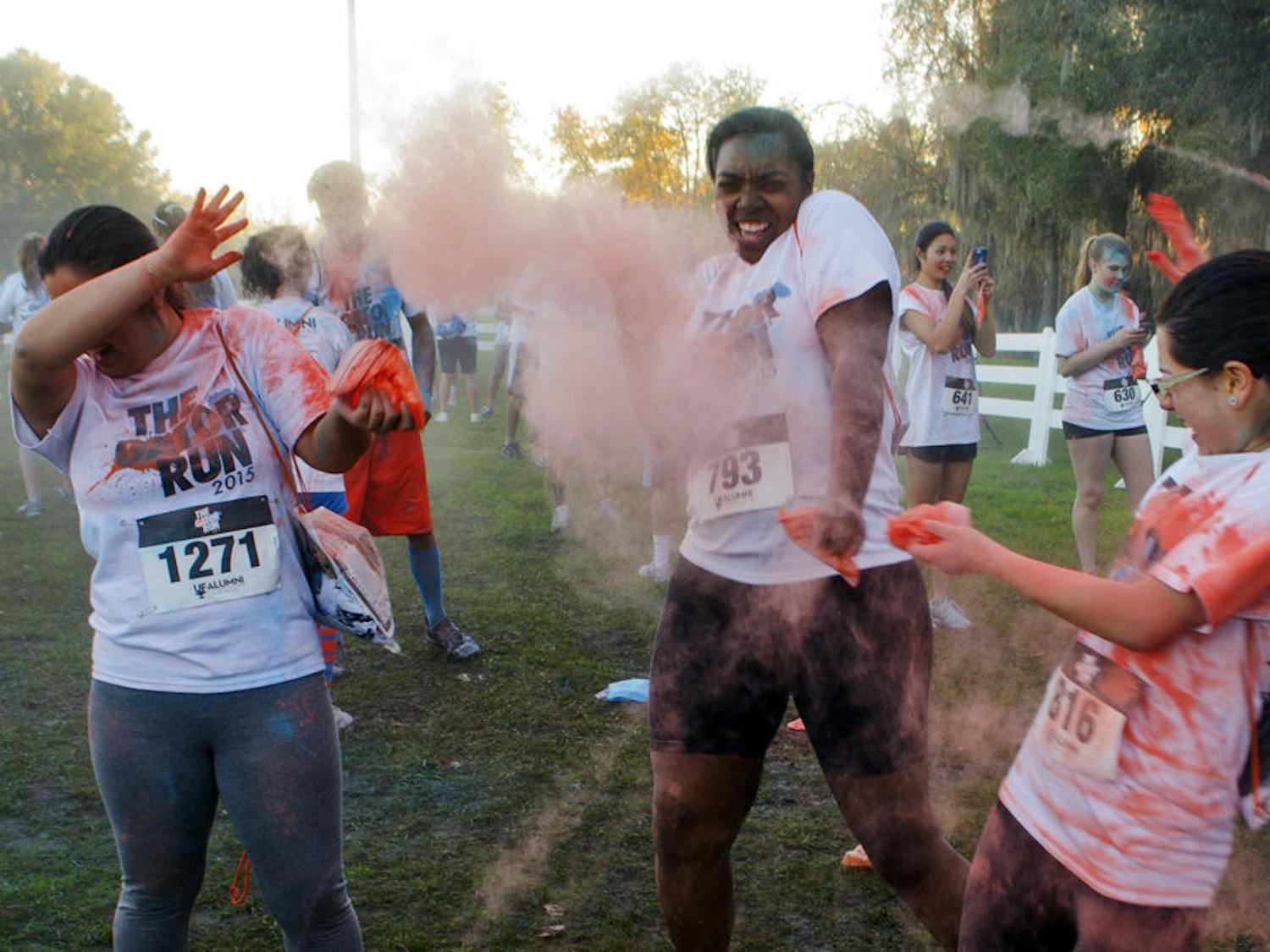 From left: Ami Wang, 20, Chelsi Gaskin, 20, and Valentina Varela, 19, all UF students, throw bags of orange corn starch at each other on Flavet Field after running their first Gator Run.