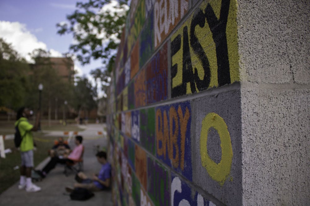 James Edouard, a 28-year-old Gainesville resident and full-time photographer and videographer, takes a picture of the Writing on the Wall event hosted by the IRHA. The event will be up until Thursday when students are going to breakdown the wall.&nbsp;