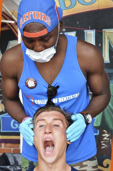 Patrick Lolo, a senior UF dental student, checks the mouth of Derek Bolser, a junior UF natural resource conservation major, during the 2nd Annual Oral Cancer Foundation 5K Run/Walk for Awareness on Bo Diddly Plaza on Saturday.