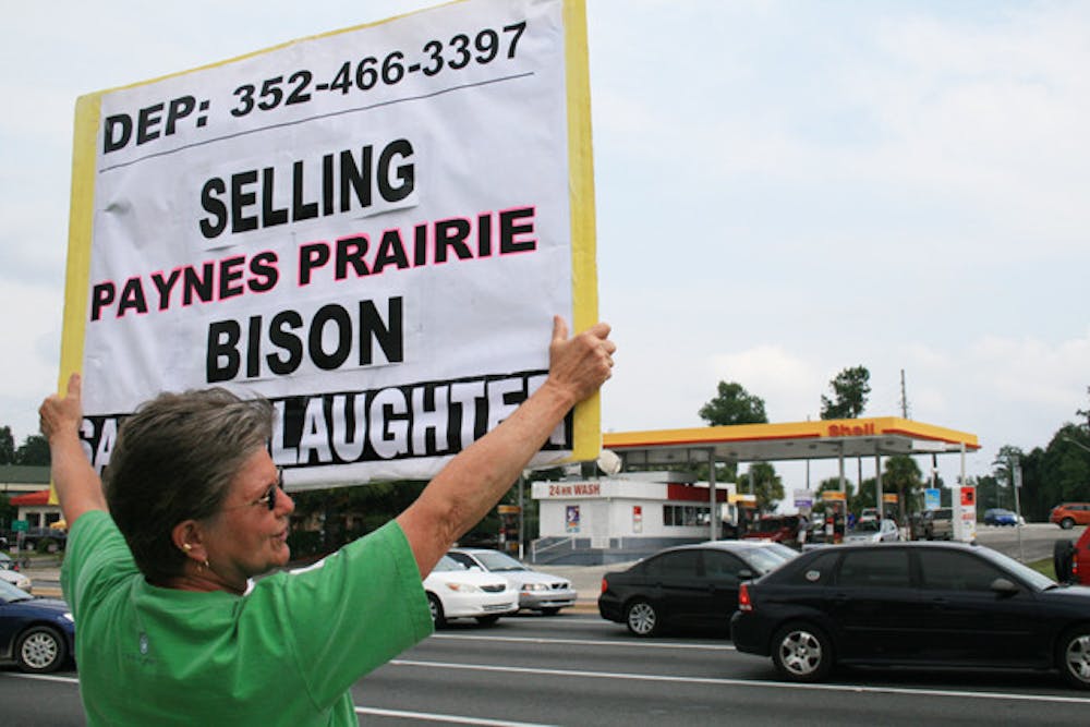 <p>Sharon Nataline, 60, holds a sign on the corner of Archer Road and 34th Street to protest for the safe treatment of the bison at Paynes Prairie Preserve State Park.</p>