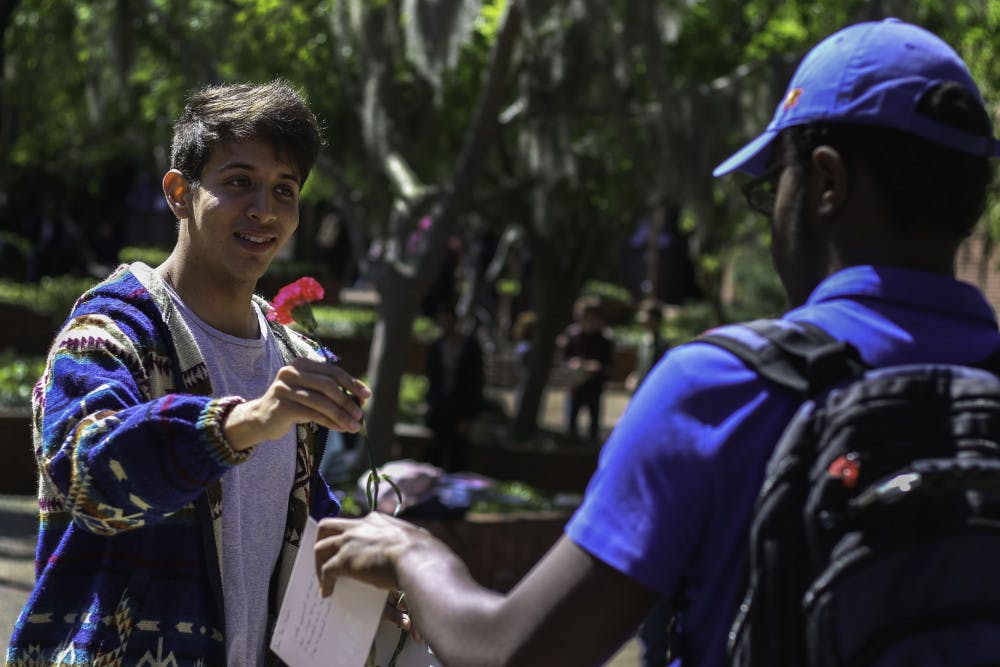 Matthew Diaz, a 21-year-old political science third year, hands a rose and thank you card Monday to Shameer Boursiquot, an 18-year-old aerospace engineering first year, to give to a bus driver for the RTS Driver Appreciation event. “I ride the bus nearly every day to and from school, and it’s always been something I’m really grateful for,” Diaz said. 