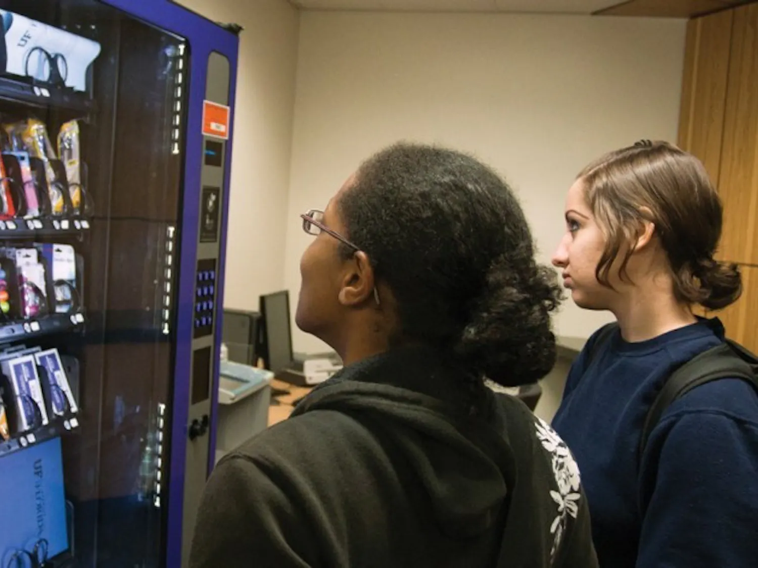 Psychology senior Jodi Wallace and biology senior Noelani Arango look at the inventory in the school-supply vending machine, located on the second floor of Library West on Tuesday afternoon.