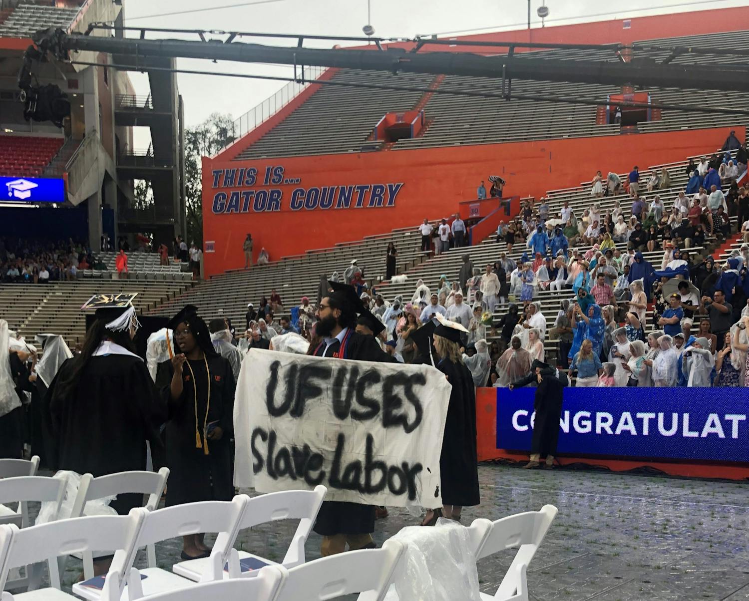 Syed Muhammad Omar holds a banner during the College of Liberal Arts and Sciences commencement ceremony on Sunday. Omar, a 27-year-old UF psychology bachelor’s graduate, said he is involved with Divest UF.