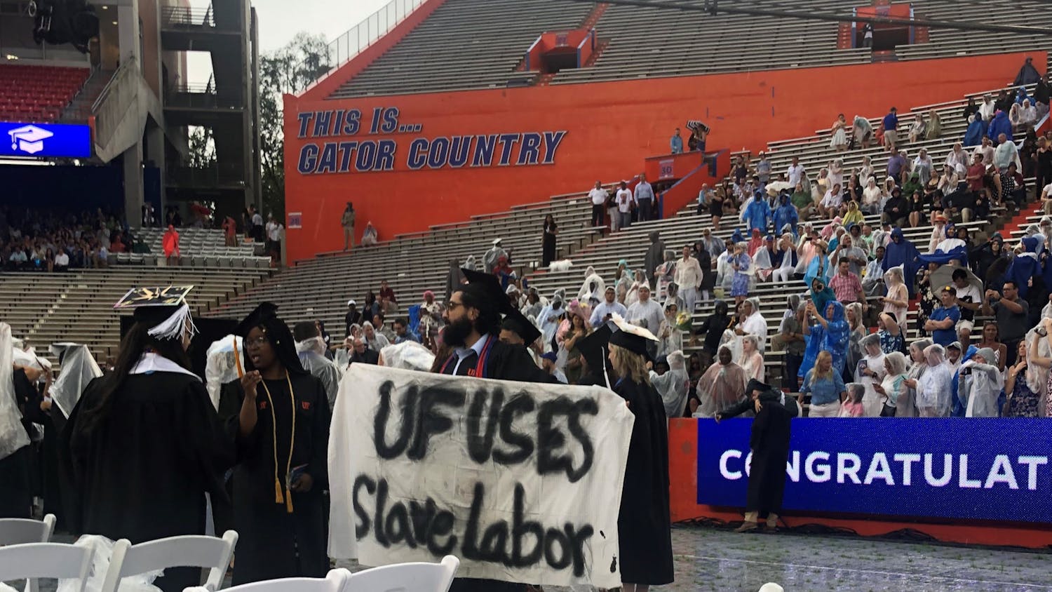 Syed Muhammad Omar holds a banner during the College of Liberal Arts and Sciences commencement ceremony on Sunday. Omar, a 27-year-old UF psychology bachelor’s graduate, said he is involved with Divest UF.