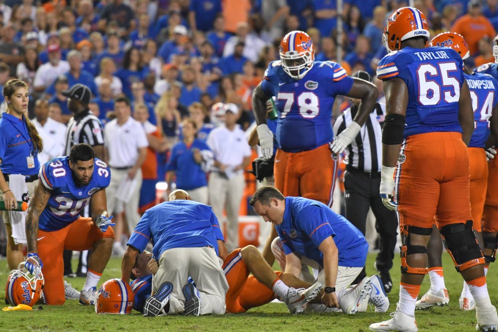 <p>Florida athletic trainers kneel beside quarterback Luke Del Rio after Del Rio was injured during Florida's 32-0 win over North Texas on Sept. 17, 2016, at Ben Hill Griffin Stadium.</p>