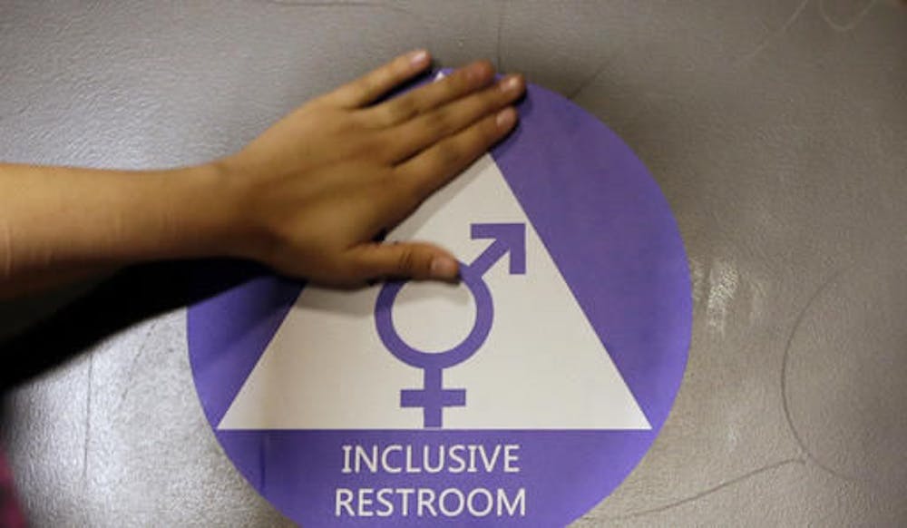 <p>In this May 17, 2016 file photo, a new sticker is placed on the door at the ceremonial opening of a gender neutral bathroom at Nathan Hale High School in Seattle. A government official says the Trump administration will revoke guidelines that say transgender students should be allowed to use bathrooms and locker rooms matching their chosen gender identity.</p>