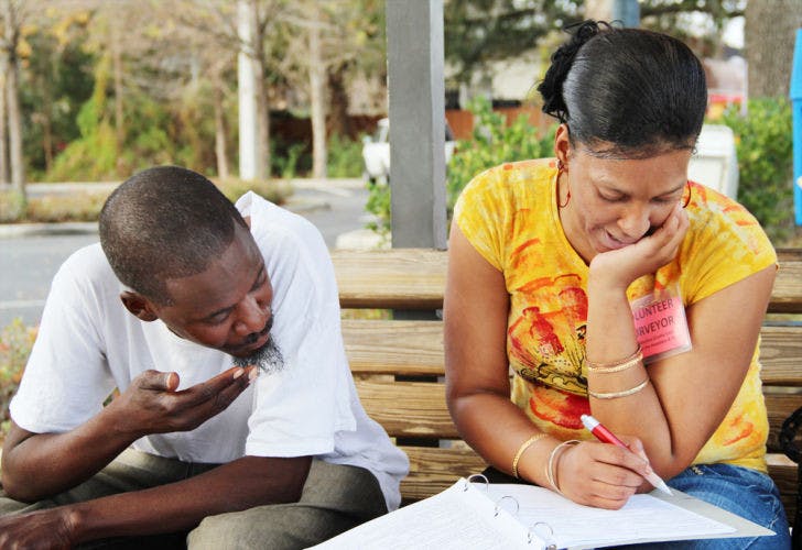 Sapphira Crawford, 36, right, a volunteer for the City of Gainesville/Alachua County Coalition for the Homeless and Hungry, helps George Washington take a survey at the bus stop in front of the Publix on 1302 N. Main St. on Tuesday afternoon.