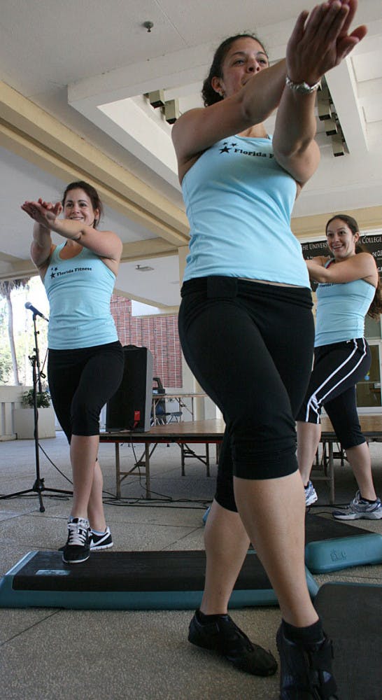 UF fitness instructors, Tricia Figueroa (front), Meaghan O'Dwyer (left) and Juliana De Oliveira (back), demonstrate a step-exercise routine Thursday for the 9 Minutes of Nakedness in the Reitz Union Colonnade.