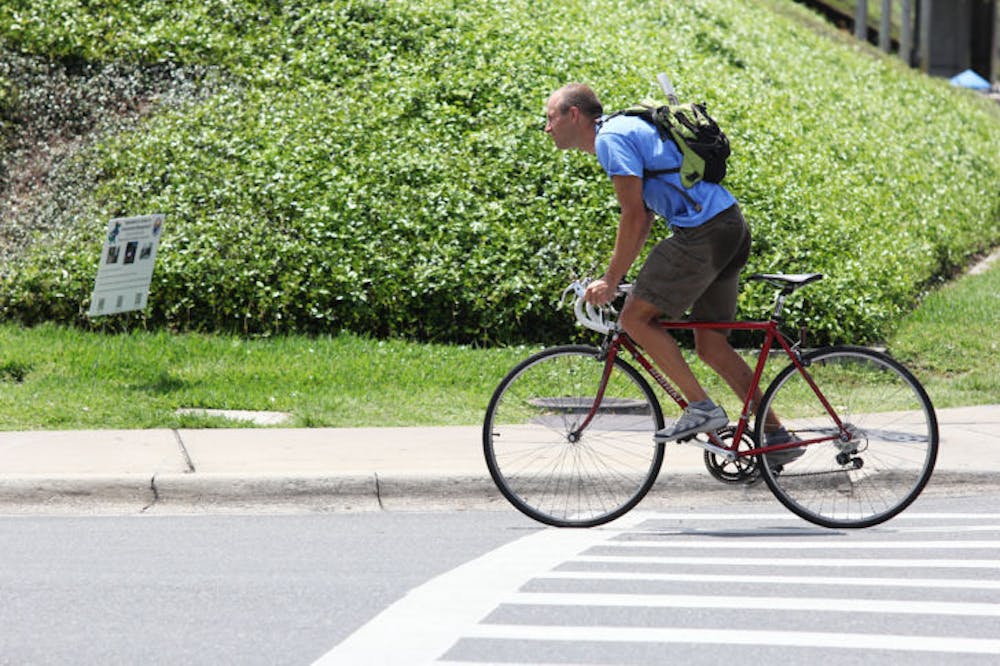 <p>A commuter rides his bike east on Museum Road on Monday afternoon. A new study shows that biking to work can be healthier than regular exercise.</p>