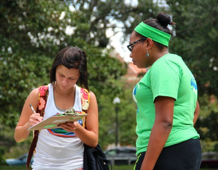 Brittany Bowen, 18, left, fills out a pledge card while Janine Monfries, 21, helps with the “Power Vote” campaign on the Plaza of the Americas on Thursday.