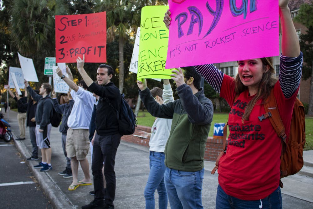 Bobby Mermer, a 32-year-old political science doctoral student and co-president of Graduate Assistants United, leads a chant Tuesday afternoon during the GatorWings Support Rally. The rally was held outside of Tigert Hall with 12 people in attendance.