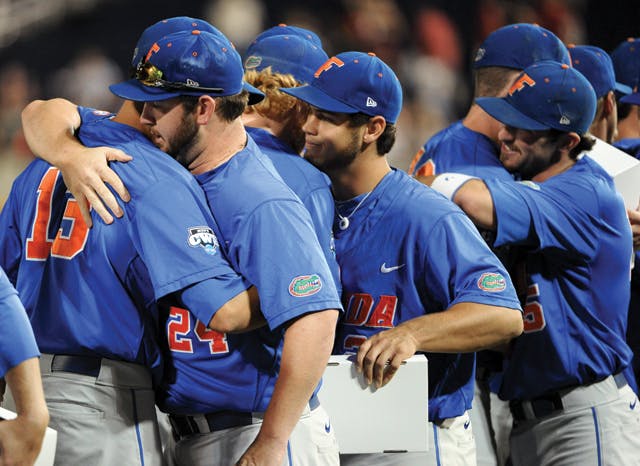 Florida players Tommy Toledo (13), Alex Panteliodis (24) and others hug after South Carolina's 5-2 win in Game 2 of the NCAA baseball College World Series best-of-three finals that gave South Carolina the title in Omaha, Neb., Tuesday, June 28, 2011. (AP Photo/Eric Francis)