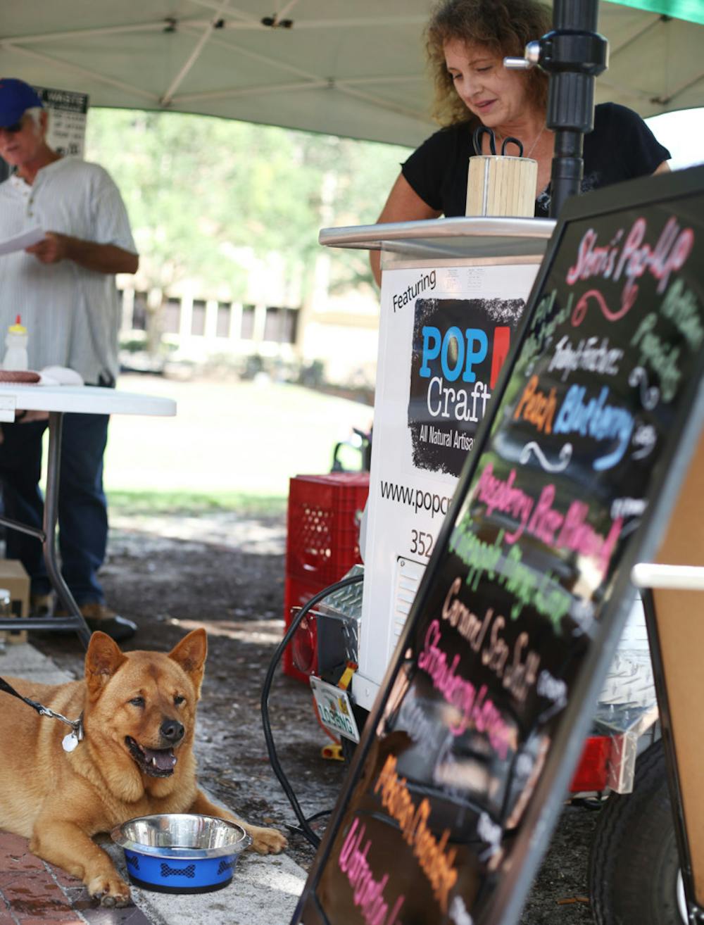 <p>Sherri McCormick, owner of Sherri’s Pop-Up Artisan Pops, serves a bowl of water to a dog during the Union Street Farmers Market Wednesday.</p>