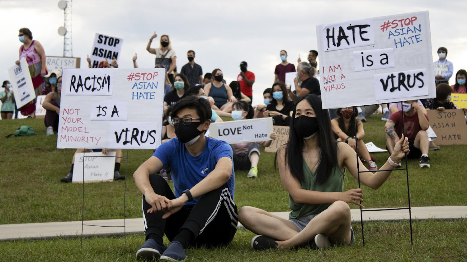Larry Wang, 29, (left) and Shirley Ai, 28, (right) sit at Depot Park as they listen to speakers during a vigil on Saturday, March 27, 2021. The vigil followed a march from Bo Diddley Plaza, which was held to raise awareness about increasing anti-Asian violence and remember the victims of the shootings that killed eight people in Atlanta.