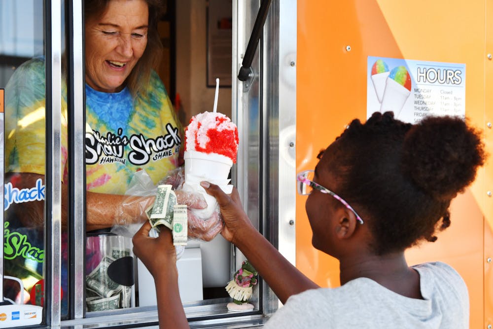 <p dir="ltr">Linda Smith hands Kalani Breen, 11, a shaved ice cup in exchange for $3.50. Breen ordered a cherry-and-cotton-candy shaved ice with marshmallow topping, one of Charlie's sweeter dessert options.</p>