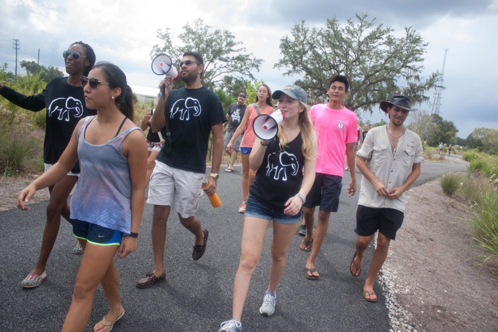 Students march for the rights of elephants and rhinos in Asia at Depot Park on Sunday afternoon.