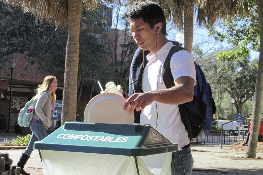 <p>Jomar Duran, a 21-year-old UF psychology senior uses one of Krishna Lunch’s first compost trash cans on Plaza of the Americas on Jan. 11, 2016.</p>