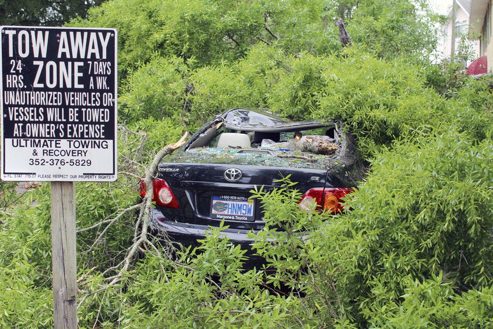 A fallen tree rests on top of a car at the corner of Northwest 18th Street and Third Avenue Thursday. Three vehicles were damaged by the falling tree.