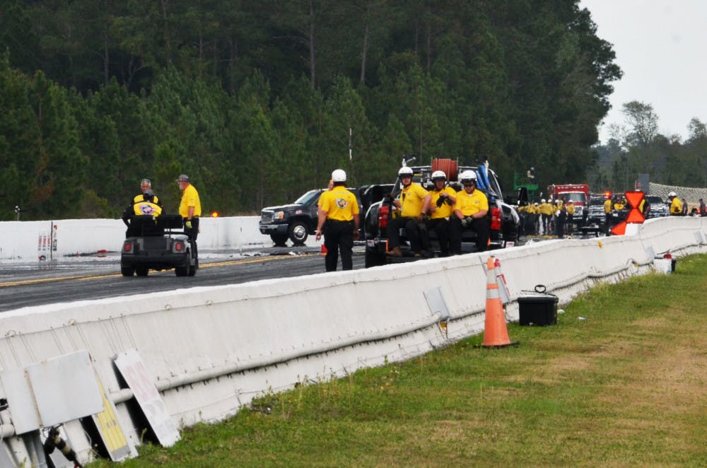 <p>Emergency officials inspect the area near the finish line at Auto Plus Raceway in Gainesville following Top Fuel drag racer Larry Dixon's crash on Saturday at the 2015 Gatornationals.</p>