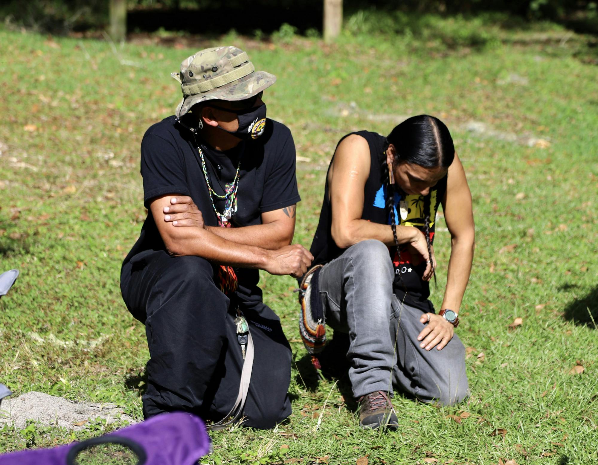 Robert Rosa (left), 52, a member of the Borinquen Taino nation and Stuart Flores (right), a member of the Algonquin Maya nation, kneel together, during the protest, in honor of their ancestors on Thursday, Dec. 3, 2020. The two explained that in Native American culture ancestors return the soil after they pass away. 