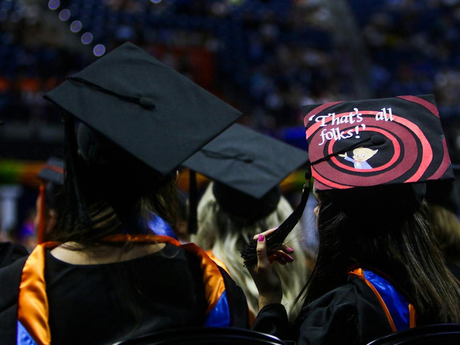A new graduate of the University of Florida watches the remainder of the ceremony while wearing a graduation cap with the Porky Pig quote, “That’s all, folks,” from Looney Tunes.