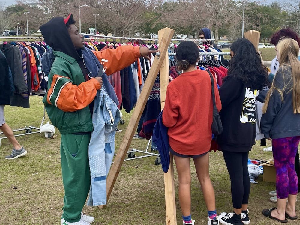 <p>Orlando vendor Brent Palmer directs customers to his racks of vintage clothes at the Florida Vintage Market Jan. 6, 2022. </p>