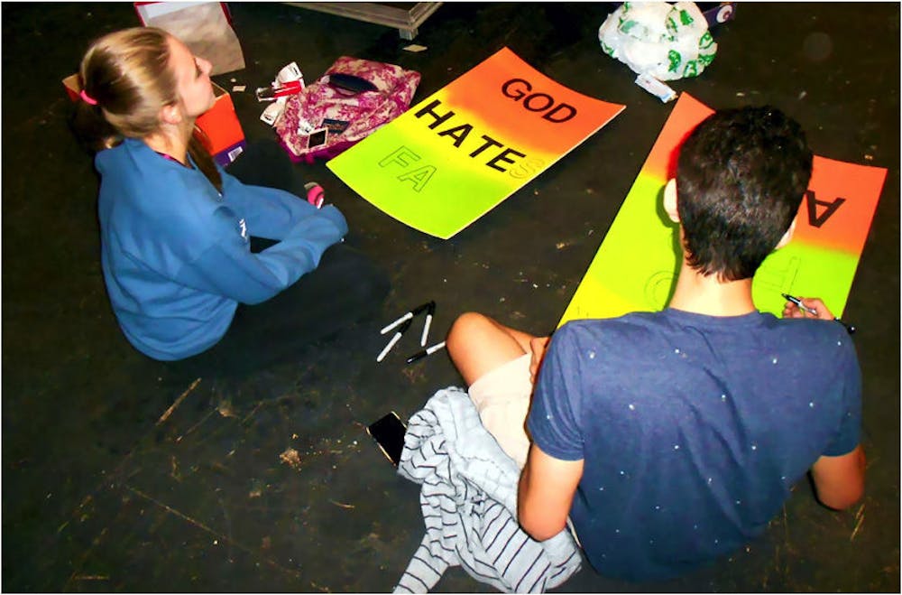 <p dir="ltr" align="justify">Stephanie Watson, 19, and Matthew Henao, 20, make protest signs that will be used for props in "Thank God for AIDS." The play premieres Friday.</p>