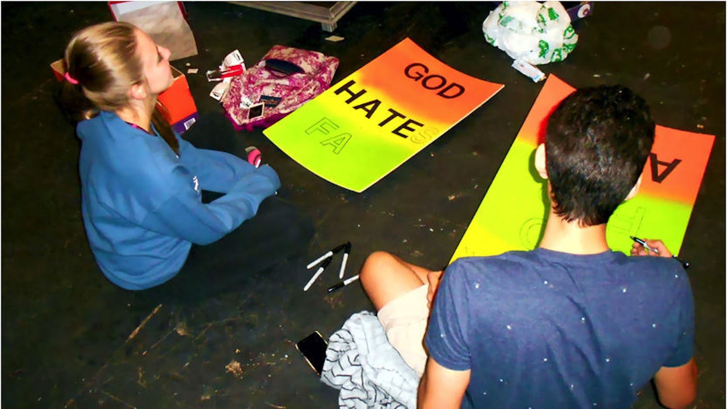 Stephanie Watson, 19, and Matthew Henao, 20, make protest signs that will be used for props in "Thank God for AIDS." The play premieres Friday.