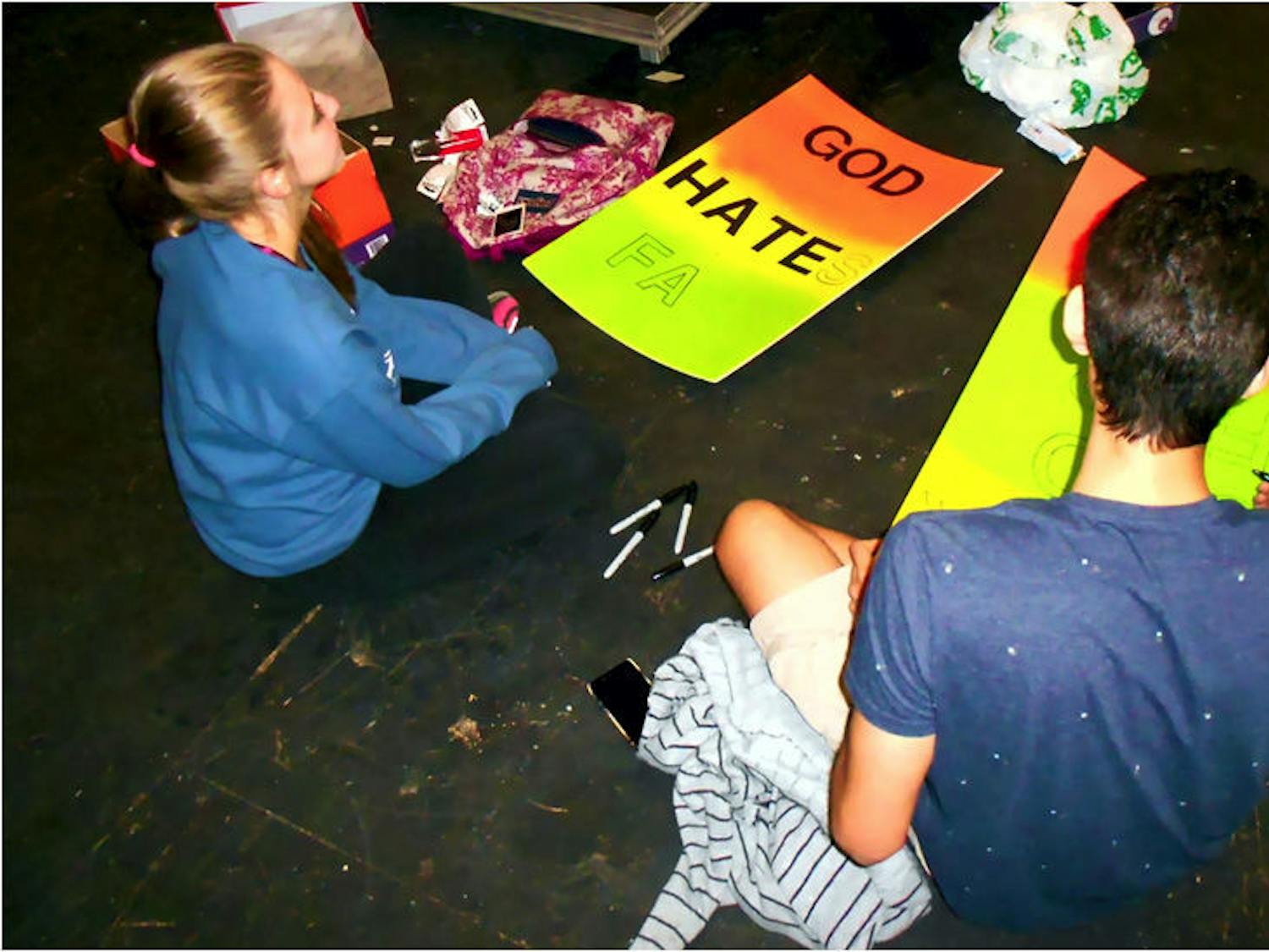 Stephanie Watson, 19, and Matthew Henao, 20, make protest signs that will be used for props in "Thank God for AIDS." The play premieres Friday.