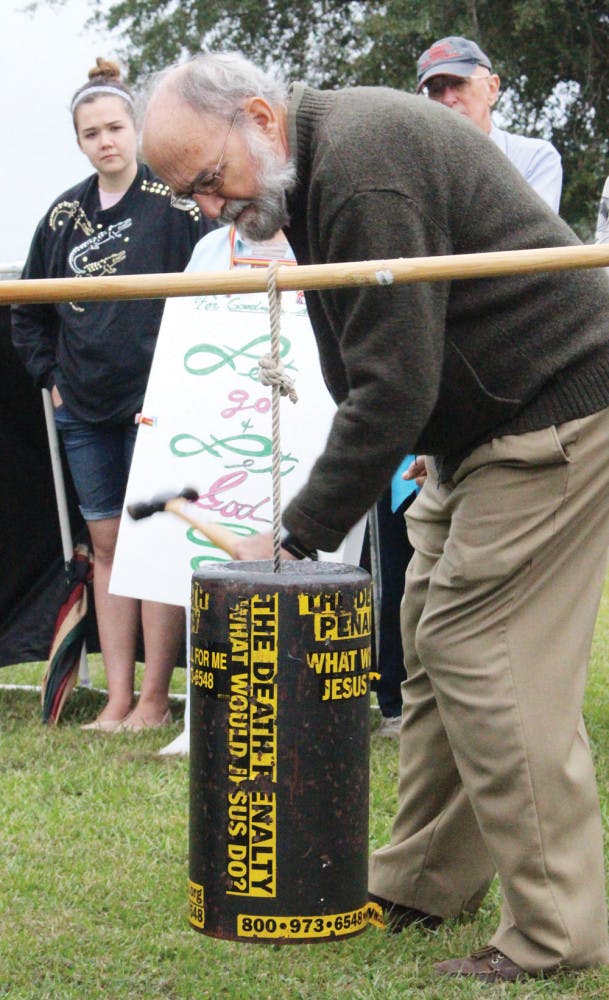 George Diller, a 73-year-old UF French prose professor, hits a bell with a hammer Tuesday at 6 p.m. to signify the execution of William Happ.
