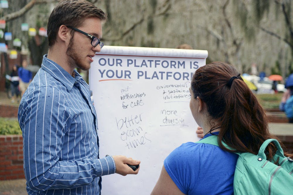 <p>Tyler Richards, an 18-year-old UF biomedical engineering freshman, speaks with a student about Access Party’s platform. Members of Access Party and Swamp Party stood around Turlington Plaza asking students for their input about issues that affected them.</p>