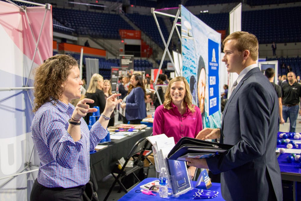 Representatives from Summit Holdings, Inc. speak to a student about the different opportunities at their company. Summit was one of the hundreds of firms and organizations present at Career Showcase in the Stephen C. O'Connell Center on Tuesday morning.