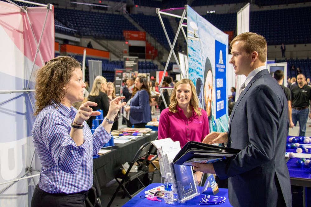 <p>Representatives from Summit Holdings, Inc. speak to a student about the different opportunities at their company. Summit was one of the hundreds of firms and organizations present at Career Showcase in the Stephen C. O'Connell Center on Tuesday morning.</p>