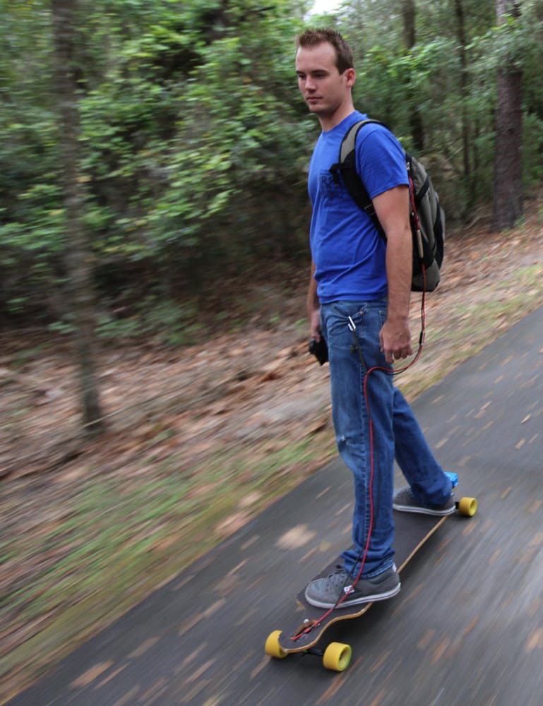 Aaron King, UF alumnus and founder of RedRock Board Shop, rides down the Gainesville-Hawthorne State Trail on one of his electric longboards Oct. 9. The electronics for a board cost $300.