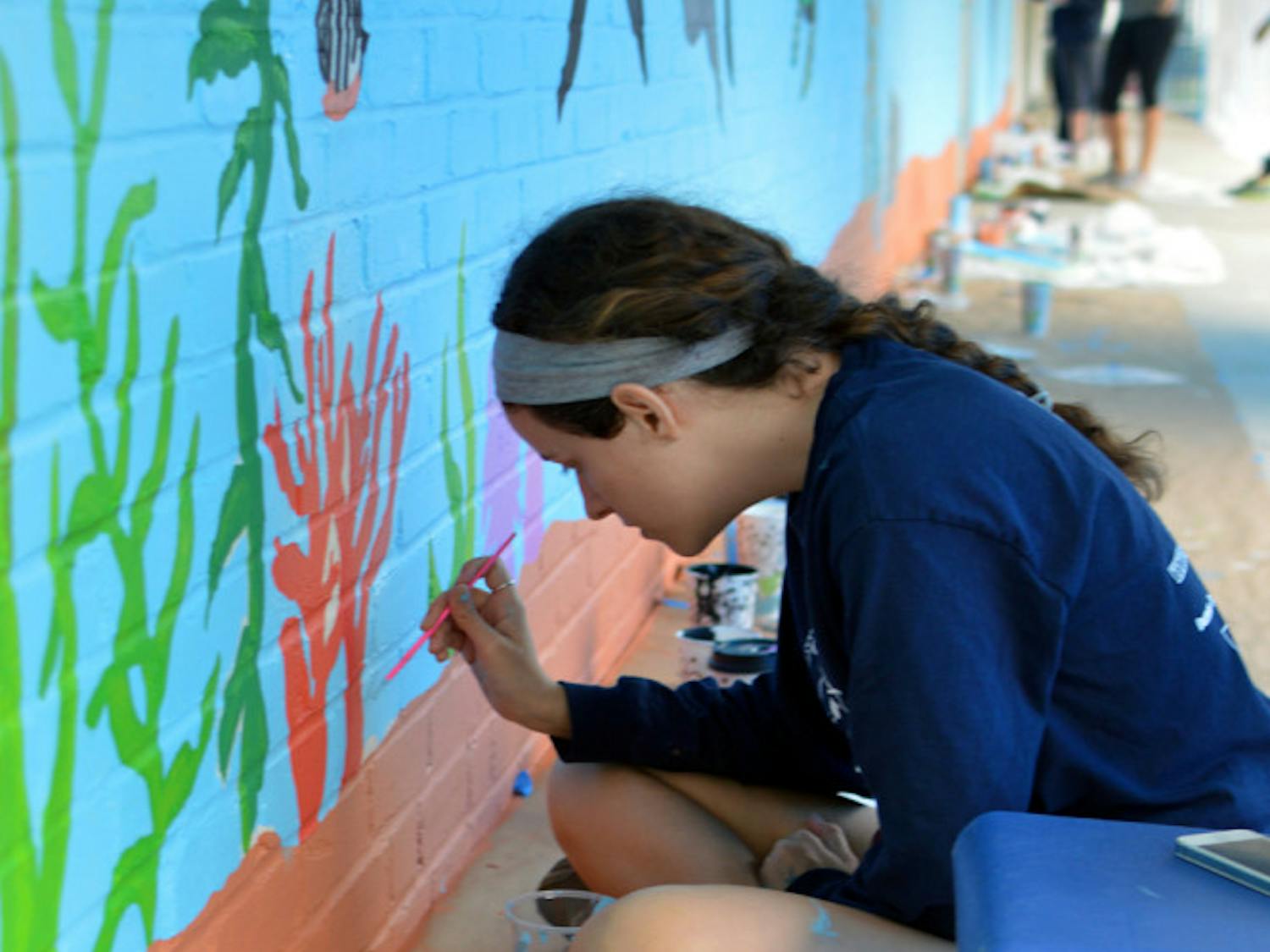 Katie Weiser, a 19-year-old UF mechanical engineering sophomore, puts the finishing touches on a mural at the Sidney Lanier Center on Sunday. 