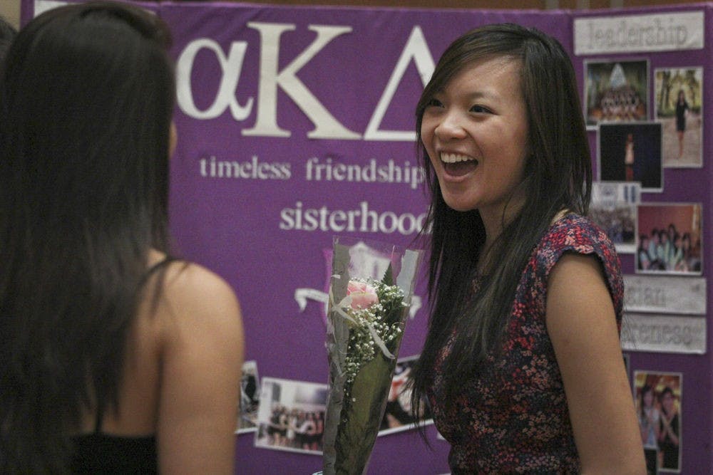 <p>Nikki Nguyen, a 21-year-old UF sociology junior and Alpha Kappa Delta Phi sister, laughs with a friend while representing her sorority at the 2015 Asian Kaleidoscope Month opening ceremony Sept. 21, 2015. "Our sorority got a pink rose for one of our sisters for her first public performance," Nguyen said.</p>