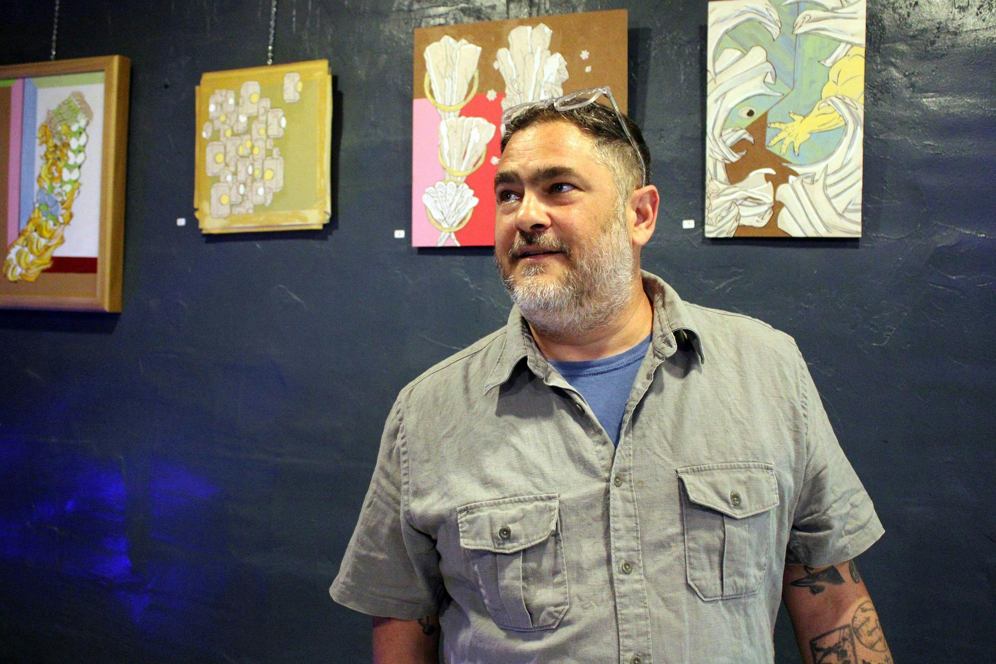 Shawn Maschino in front of his art displayed at Dad’s Bar located in THE AUK MARKET in Gainesville, Fla. on May 27, 2026. (Photo by Riana Sage)
