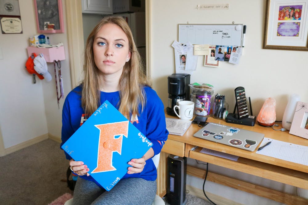 Elizabeth Stout, Parkland survivor and UF political science freshman, shows the cap she made for her graduation from Marjory Stoneman Douglas High School. Stout says she wants it to honor the four seniors that were unable to graduate due to the tragedy: Carmen Schentrup, Nicholas Dworet, Meadow Pollack and Joaquin Oliver.