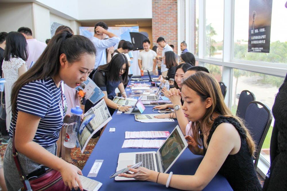 Shuyan Ding, right, a 23-year-old electrical engineering graduate student, teaches an incoming freshman about an English translation application. Ding volunteers with the Chinese Student Association.