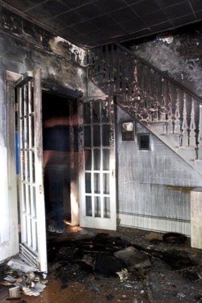 Kevin Williams, an attorney who works at the law office located in the historic Fennel-Waldo House, looks through charred remains on the floor of the office, located at 719 NE First St., which caught fire Wednesday night.